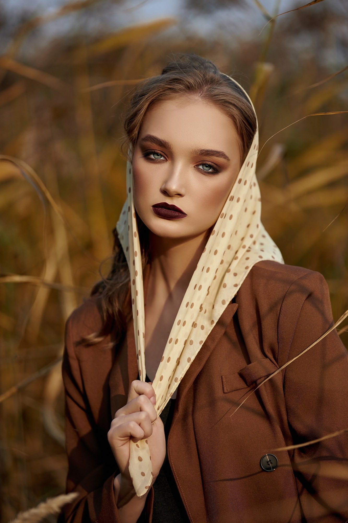 Portrait of a beautiful fashion woman in a thicket of autumn grass